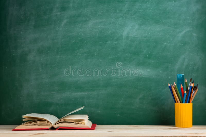 Education and reading concept - group of colorful books on the wooden table in the classroom, blackboard background