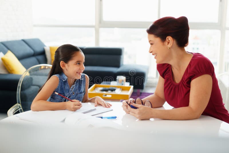Educação com a filha de ajuda da mamã que faz trabalhos de casa da escola em casa fotografia de stock Educação com a filha de ajuda da mamã que faz trabalhos de casa da escola em casa fotografia de stock