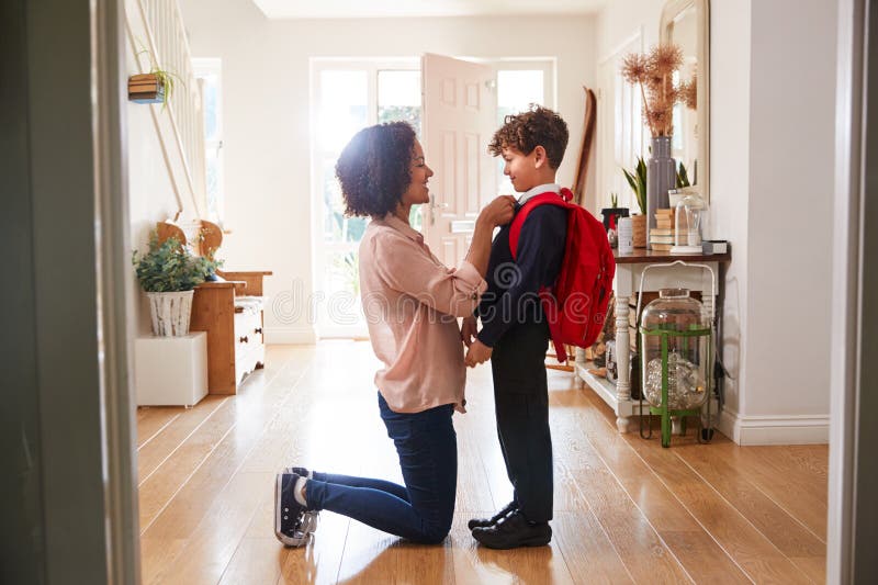 Single Mother At Home Getting Son Wearing Uniform Ready For First Day Of School. Single Mother At Home Getting Son Wearing Uniform Ready For First Day Of School