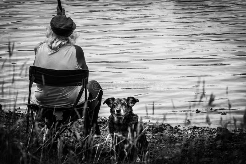 Een alleenstaande vrouw en haar voogd-hond vissen op het Cassière-meer