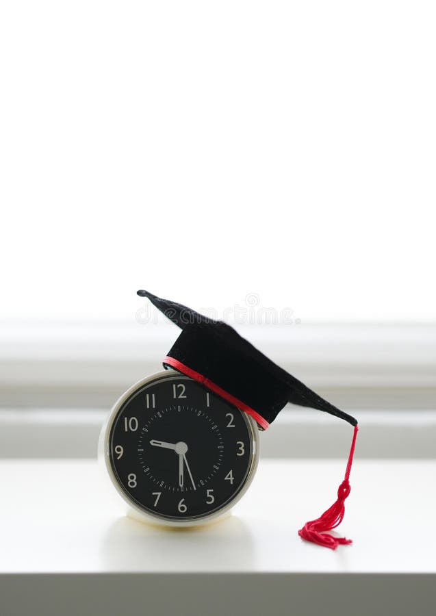 Een baret op een wekker op witte achtergrond stock fotografie Een baret op een wekker op witte achtergrond stock fotografie