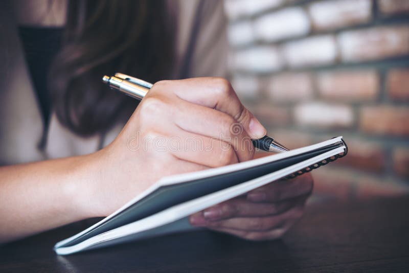 Closeup image of a business woman writing and taking note on notebook in office. Closeup image of a business woman writing and taking note on notebook in office