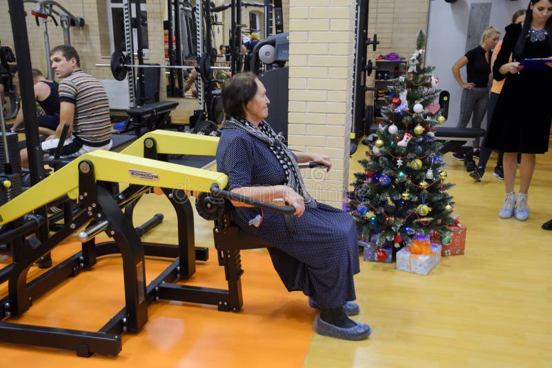 Een bejaarde is bezig geweest met de gymnastiek op de simulator stock foto Een bejaarde is bezig geweest met de gymnastiek op de simulator stock foto