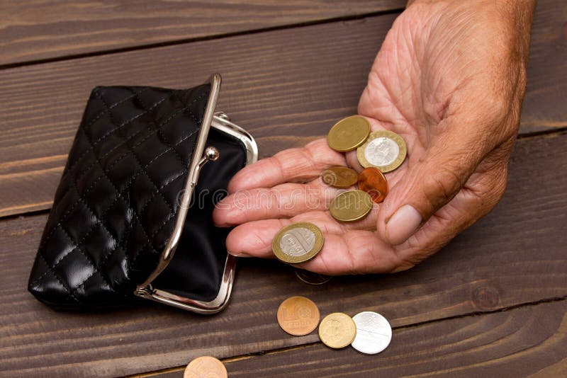 Een bejaarde persoon houdt de muntstukken over de oude lege portefeuille Het concept armoede in pensionering stock foto Een bejaarde persoon houdt de muntstukken over de oude lege portefeuille Het concept armoede in pensionering stock foto
