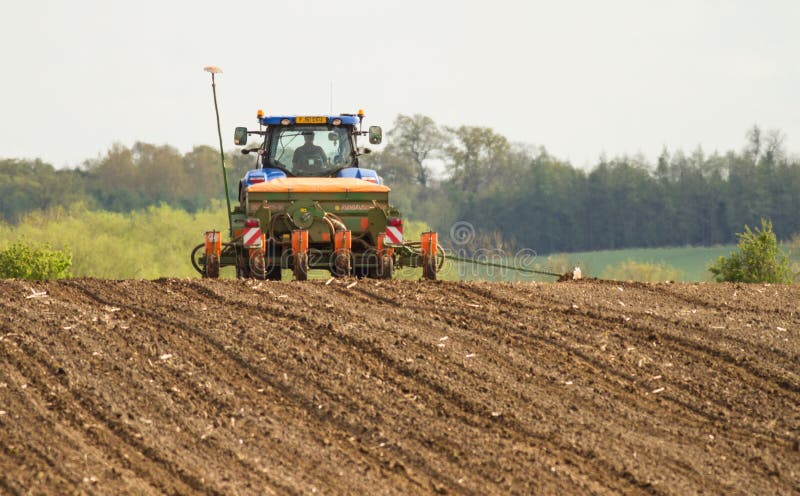 Een blauwe tractor met een zaadboor op een geploegd gebied stock afbeeldingen Een blauwe tractor met een zaadboor op een geploegd gebied stock afbeeldingen