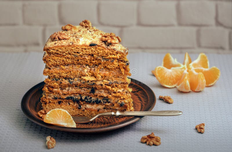 Een brok van eigengemaakte cake op een ceramische plaat met noten en mandarin royalty-vrije stock foto Een brok van eigengemaakte cake op een ceramische plaat met noten en mandarin royalty-vrije stock foto