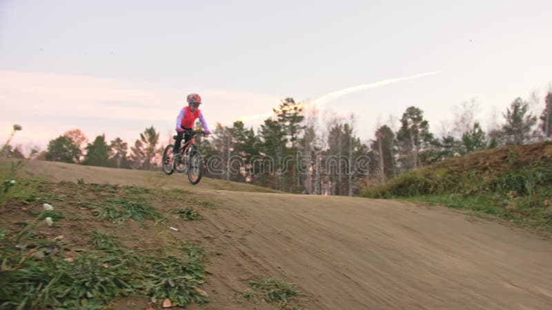 Een caucasisch kind rijdt fietsweg in het vuilpark Meisje op de zwarte oranje cyclus in racetrack Kid gaat wel.