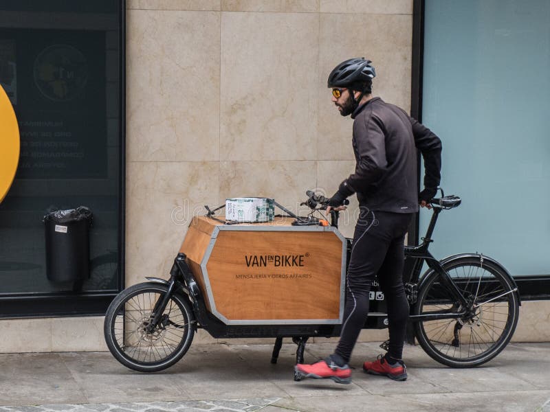 Een Coruna, de Mannelijke koerier van Spanje van Vanenbikke-bedrijf met fiets die pakketten in de stad leveren royalty-vrije stock foto Een Coruna, de Mannelijke koerier van Spanje van Vanenbikke-bedrijf met fiets die pakketten in de stad leveren royalty-vrije stock foto