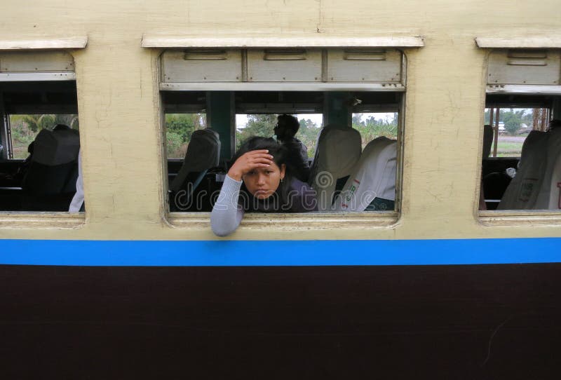 Een droevig en vermoeid Birmaans meisje die uit het venster van een oude trein kijken royalty-vrije stock foto's Een droevig en vermoeid Birmaans meisje die uit het venster van een oude trein kijken royalty-vrije stock foto's