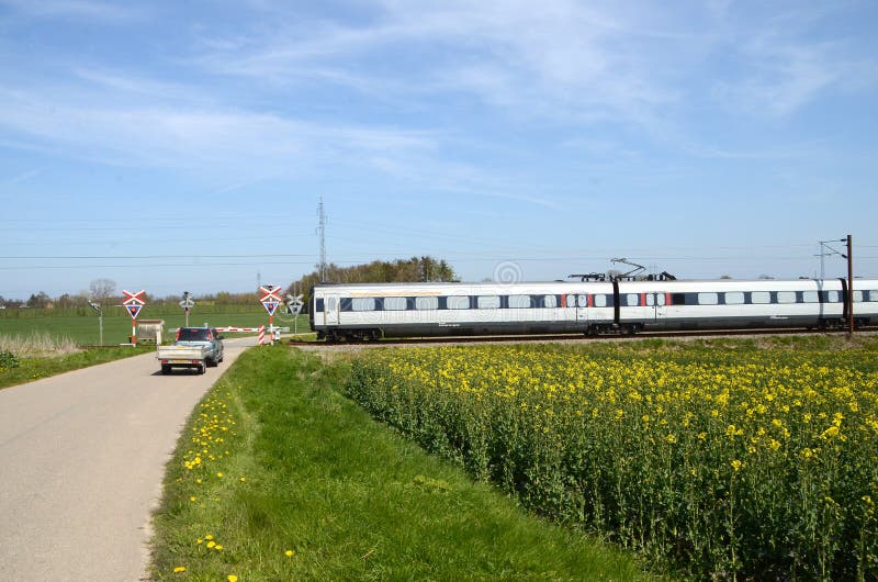 Een EMOEtrein gaat een spoorwegovergang met een het wachten auto over royalty-vrije stock afbeeldingen Een EMOEtrein gaat een spoorwegovergang met een het wachten auto over royalty-vrije stock afbeeldingen