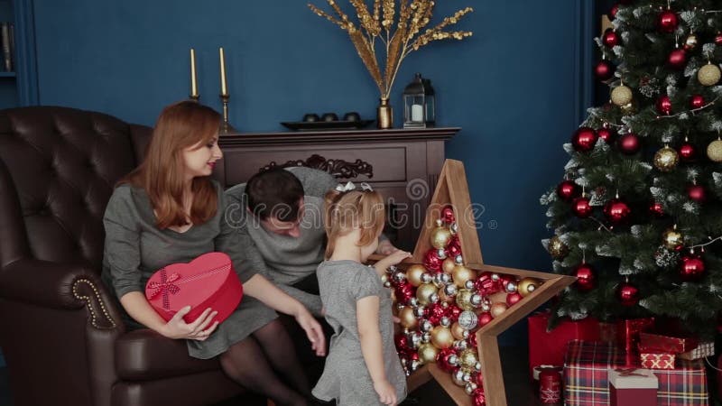 Een familie van drie opent de giften van het Nieuwjaar dichtbij de open haard, Kerstmis 2019 stock videobeelden Een familie van drie opent de giften van het Nieuwjaar dichtbij de open haard, Kerstmis 2019 stock videobeelden
