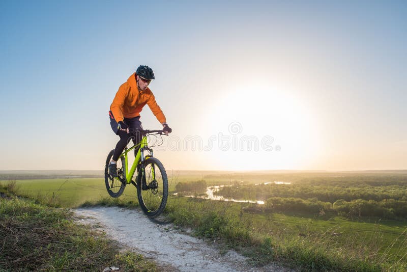 Een fietser in oranje hoodie berijdt een fiets langs een bergweg Het concept extreme sporten royalty-vrije stock foto's Een fietser in oranje hoodie berijdt een fiets langs een bergweg Het concept extreme sporten royalty-vrije stock foto's