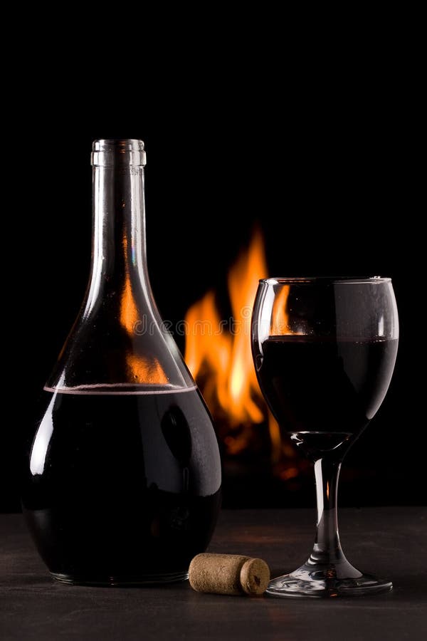 Een fles rode wijn en een glas voor een open haard royalty-vrije stock fotografie Een fles rode wijn en een glas voor een open haard royalty-vrije stock fotografie