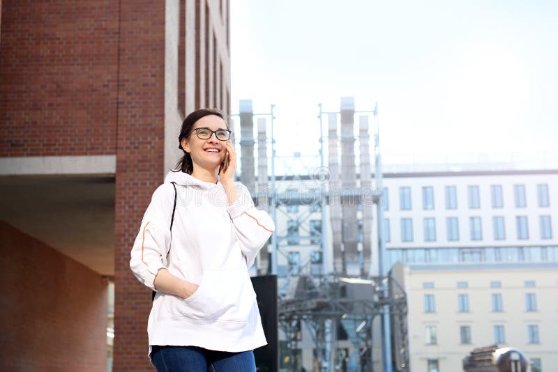 Een gang in het stadscentrum, een jonge vrouw die rond de stad lopen die op een mobiele telefoon spreken stock afbeelding Een gang in het stadscentrum, een jonge vrouw die rond de stad lopen die op een mobiele telefoon spreken stock afbeelding