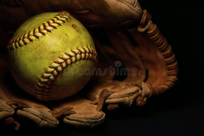 Een geel softball in een oude, bruine, leerhandschoen