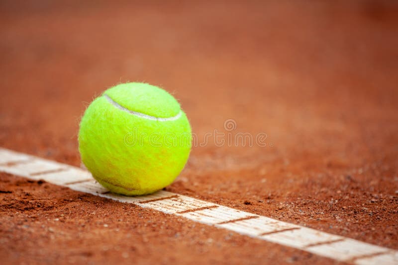 Een gele tennisbal ligt op de kleirechtbank stock afbeelding Een gele tennisbal ligt op de kleirechtbank stock afbeelding