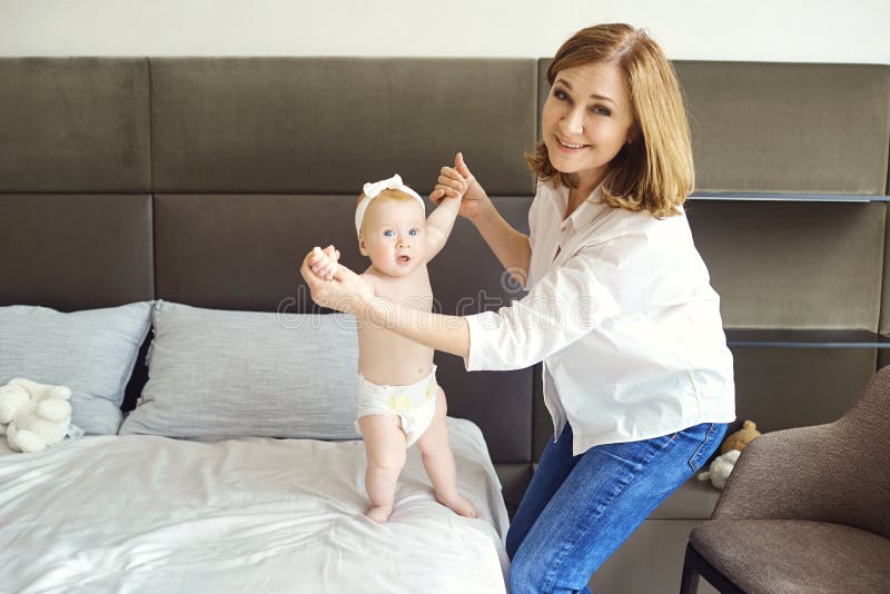 Een gelukkige grootmoederspelen met babykleinzoon op het bed stock foto's Een gelukkige grootmoederspelen met babykleinzoon op het bed stock foto's
