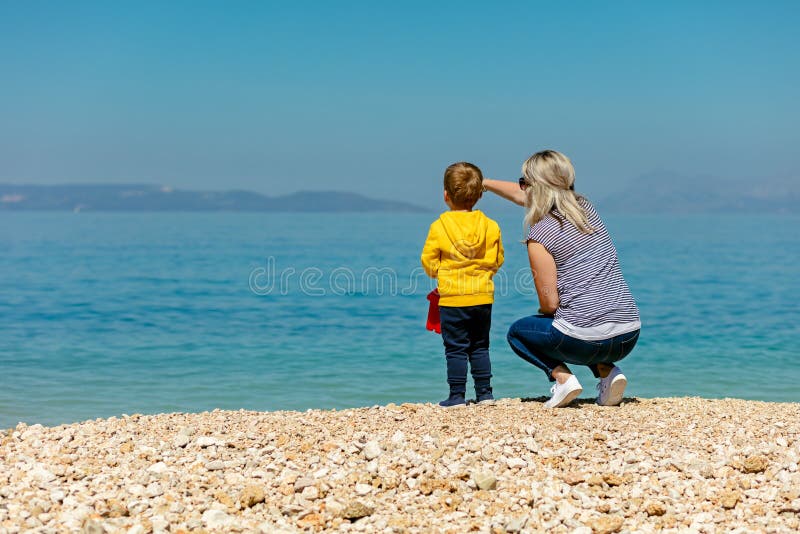 Een gelukkige moeder en jong kindjongenszoon die pret op een zonnig strand hebben royalty-vrije stock foto Een gelukkige moeder en jong kindjongenszoon die pret op een zonnig strand hebben royalty-vrije stock foto