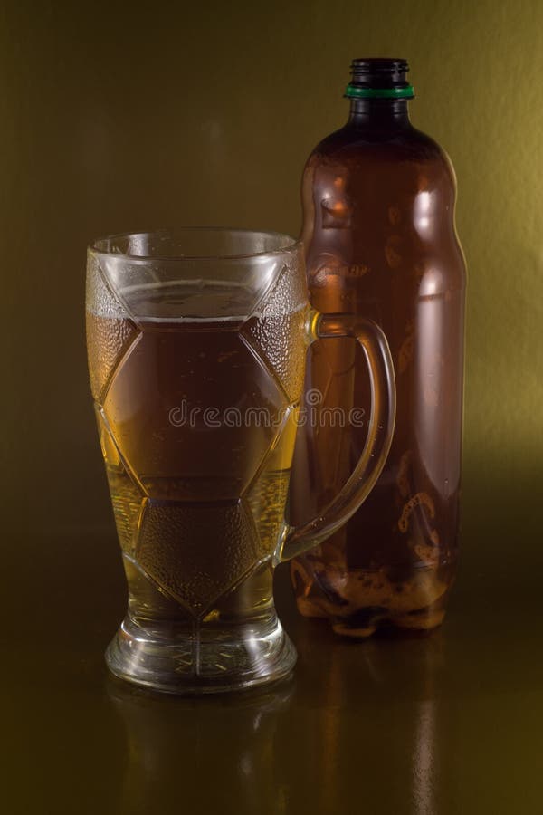 Een glas bier naast een lege plastic fles royalty-vrije stock afbeelding Een glas bier naast een lege plastic fles royalty-vrije stock afbeelding