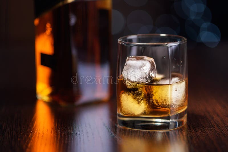 Een glas van whisky op de rotsen en een fles op de lijst stock afbeeldingen Een glas van whisky op de rotsen en een fles op de lijst stock afbeeldingen
