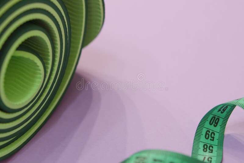 Een groene metende band verdraaide in een spiraal en een mat voor fitne stock afbeelding Een groene metende band verdraaide in een spiraal en een mat voor fitne stock afbeelding