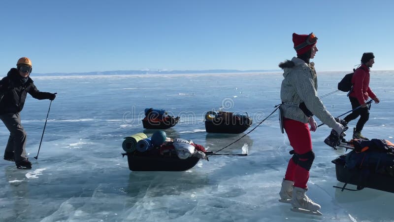 Een groep toeristen reist op schaatsen op het ijs van het diepgevroren meer baikal.