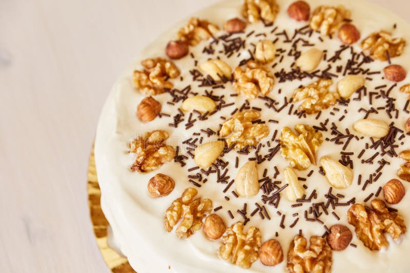 Een grote heerlijke pastei met okkernoten Eigengemaakte pastei met wit bovenste laagje en chocoladeschilfers op een witte houten royalty-vrije stock foto Een grote heerlijke pastei met okkernoten Eigengemaakte pastei met wit bovenste laagje en chocoladeschilfers op een witte houten royalty-vrije stock foto