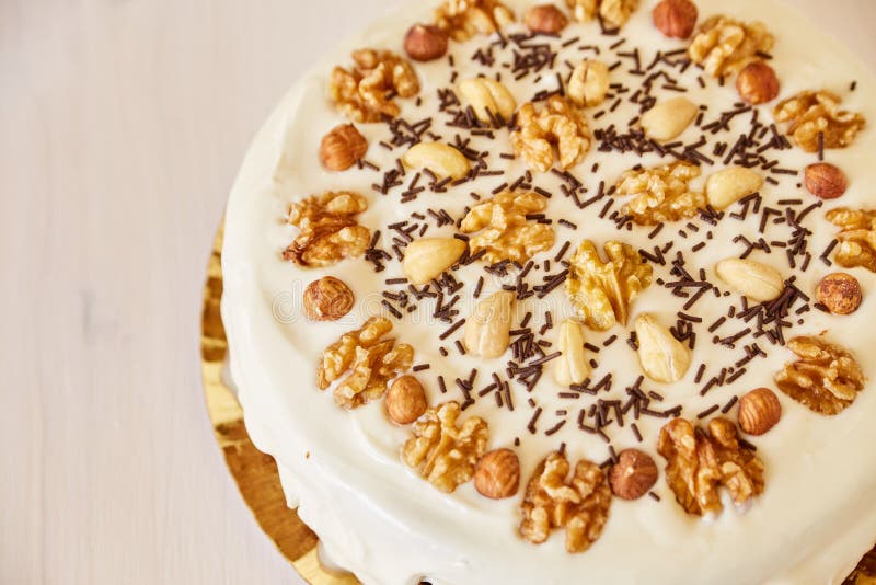 Een grote heerlijke pastei met okkernoten Eigengemaakte pastei met wit bovenste laagje en chocoladeschilfers op een witte houten stock afbeeldingen Een grote heerlijke pastei met okkernoten Eigengemaakte pastei met wit bovenste laagje en chocoladeschilfers op een witte houten stock afbeeldingen