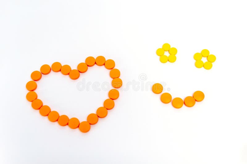 Een hart en een glimlach zijn door oranje die pillen op witte achtergrond worden geïsoleerd Het concept van de geneeskunde royalty-vrije stock foto Een hart en een glimlach zijn door oranje die pillen op witte achtergrond worden geïsoleerd Het concept van de geneeskunde royalty-vrije stock foto