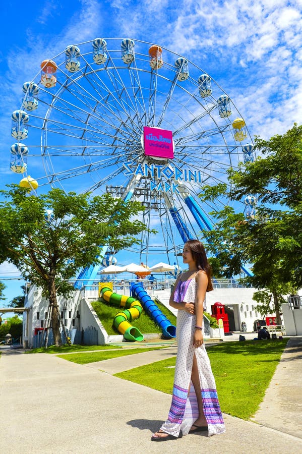 Een het glimlachen meisjestribune voor kleurrijke ferris rijdt in Santorini-Park royalty-vrije stock afbeelding Een het glimlachen meisjestribune voor kleurrijke ferris rijdt in Santorini-Park royalty-vrije stock afbeelding