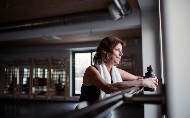 Een hogere vrouw in gymnastiek die na het doen van oefening rusten De ruimte van het exemplaar royalty-vrije stock fotografie Een hogere vrouw in gymnastiek die na het doen van oefening rusten De ruimte van het exemplaar royalty-vrije stock fotografie