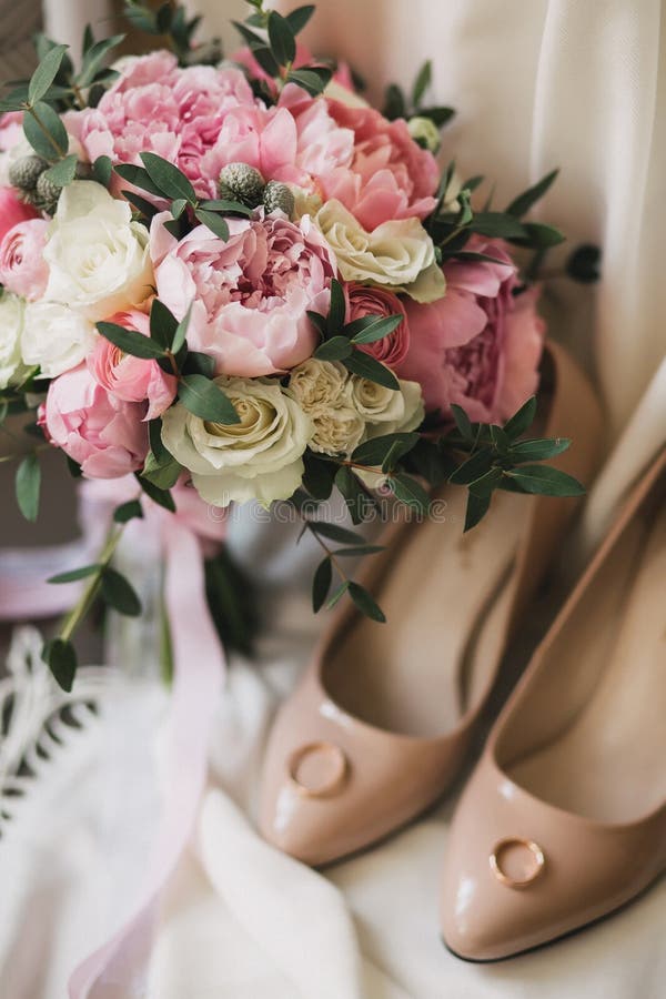 Een huwelijksboeket van roze pioenen, witte rozen, en eucalyptus, naast beige vrouwen` s schoenen royalty-vrije stock foto Een huwelijksboeket van roze pioenen, witte rozen, en eucalyptus, naast beige vrouwen` s schoenen royalty-vrije stock foto