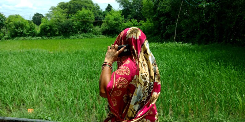 Een Indiase dorpsvrouw die praat met mensen die mobiele telefoons gebruiken royalty-vrije stock afbeelding Een Indiase dorpsvrouw die praat met mensen die mobiele telefoons gebruiken royalty-vrije stock afbeelding