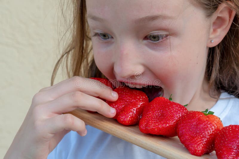 Een jong meisje eet aardbeien Allergie in een kind Rood gezicht van aardbeien royalty-vrije stock foto Een jong meisje eet aardbeien Allergie in een kind Rood gezicht van aardbeien royalty-vrije stock foto