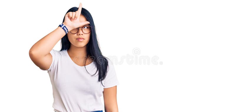 Een jong , mooi aziatisch meisje met handtele kleren en bril die grappen maken over mensen met vingers op voorhoofd die een loser