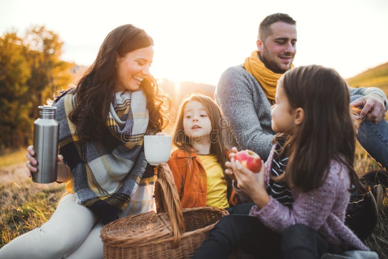 Een jonge familie met twee kleine kinderen die picknick in de herfstaard hebben bij zonsondergang royalty-vrije stock foto's Een jonge familie met twee kleine kinderen die picknick in de herfstaard hebben bij zonsondergang royalty-vrije stock foto's