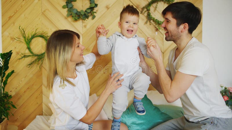 Een jonge familie met weinig zoonsspel op bed in de slaapkamer royalty-vrije stock afbeelding Een jonge familie met weinig zoonsspel op bed in de slaapkamer royalty-vrije stock afbeelding