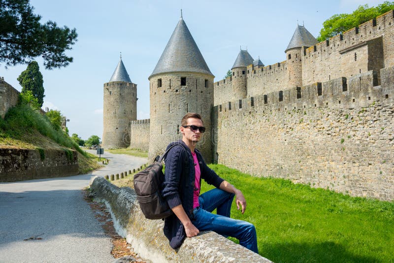 Een jonge kerel met rugzak zit dichtbij vestingsmuur van medieva royalty-vrije stock fotografie Een jonge kerel met rugzak zit dichtbij vestingsmuur van medieva royalty-vrije stock fotografie