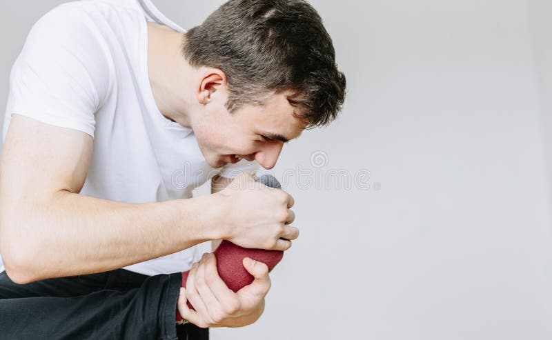 Een jonge mens snuift zijn sokken, houdend zijn voet in zijn hand Ge?soleerde grijze achtergrond stock foto's Een jonge mens snuift zijn sokken, houdend zijn voet in zijn hand Ge?soleerde grijze achtergrond stock foto's