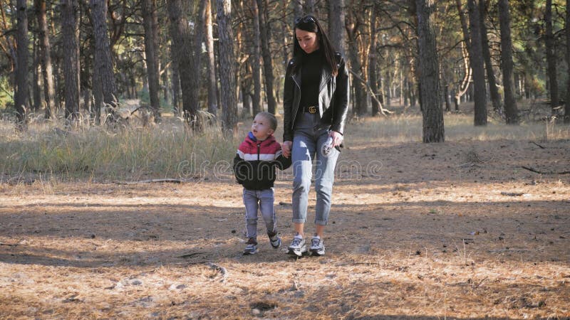 Een jonge moeder die met een kleine jongen in het herfstbos lopen.