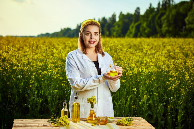 Een jonge mooie bioloog of een agronoom onderzoeken de kwaliteit van raapzaadolie op een verkrachtingsgebied Landbouwindustriecon royalty-vrije stock afbeeldingen Een jonge mooie bioloog of een agronoom onderzoeken de kwaliteit van raapzaadolie op een verkrachtingsgebied Landbouwindustriecon royalty-vrije stock afbeeldingen