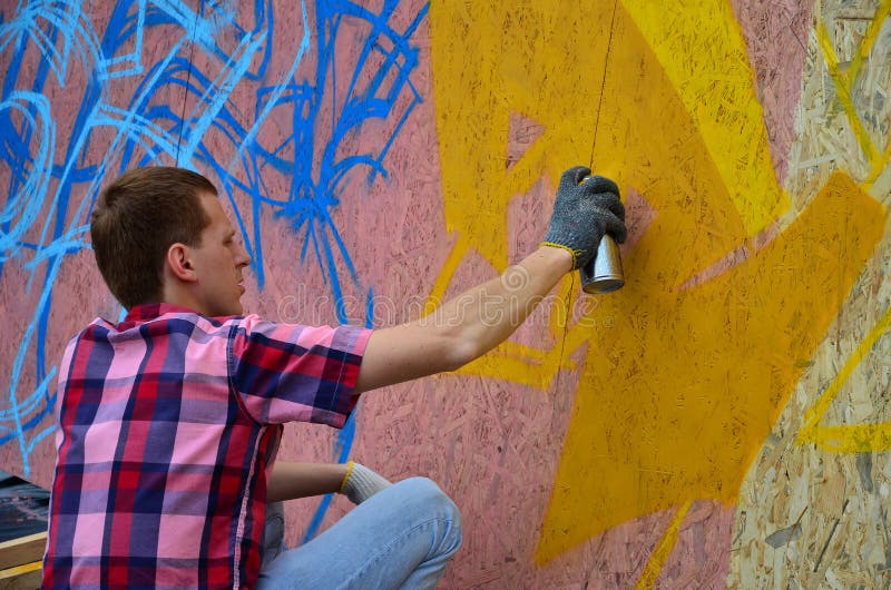 Een jonge roodharige graffitikunstenaar schildert een nieuwe graffiti op de muur stock foto's Een jonge roodharige graffitikunstenaar schildert een nieuwe graffiti op de muur stock foto's