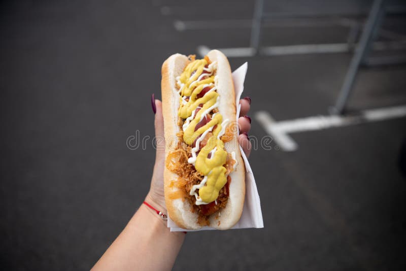 Een jonge vrouw houdt een gebeten hotdog royalty-vrije stock foto Een jonge vrouw houdt een gebeten hotdog royalty-vrije stock foto