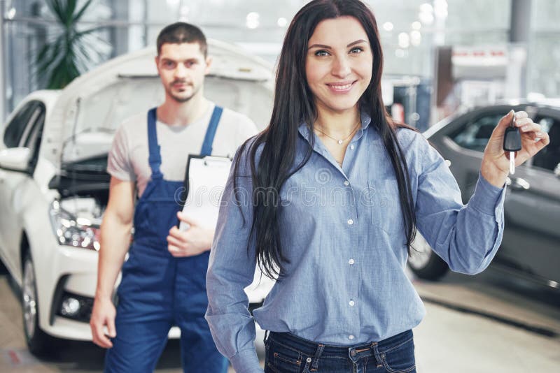 Een jonge vrouw neemt een auto van het centrum van de autodienst Zij is gelukkig omdat het werk volkomen wordt gedaan royalty-vrije stock fotografie Een jonge vrouw neemt een auto van het centrum van de autodienst Zij is gelukkig omdat het werk volkomen wordt gedaan royalty-vrije stock fotografie
