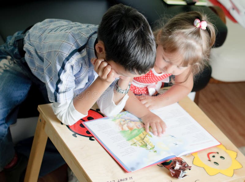 Een jongen en zijn zuster lezen een boek royalty-vrije stock fotografie Een jongen en zijn zuster lezen een boek royalty-vrije stock fotografie