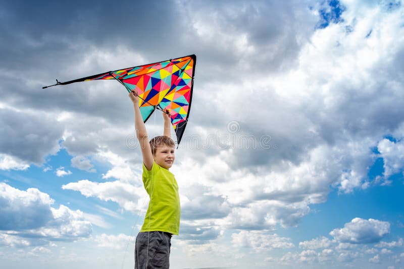 Een jongen met een kleurrijke vlieger in zijn handen tegen de blauwe hemel met wolken Conceptuele fotografie stock foto's Een jongen met een kleurrijke vlieger in zijn handen tegen de blauwe hemel met wolken Conceptuele fotografie stock foto's