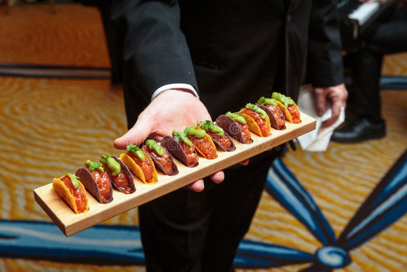 Een kelner die een houten schotelhoogtepunt van tacovoorgerechten houden - de reeks van de huwelijkscatering royalty-vrije stock afbeelding Een kelner die een houten schotelhoogtepunt van tacovoorgerechten houden - de reeks van de huwelijkscatering royalty-vrije stock afbeelding