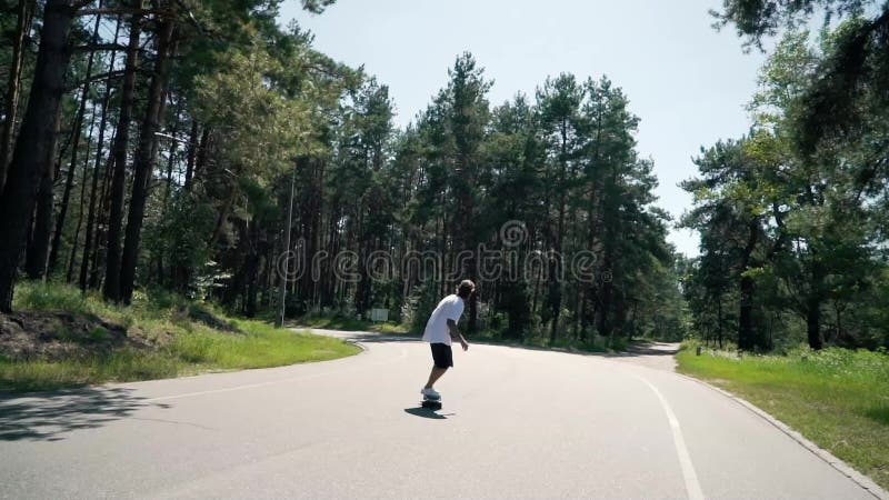 Een kerel berijdt een skateboard op een lege weg