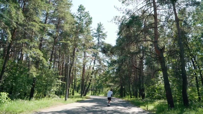 Een kerel berijdt een skateboard op een lege weg in park