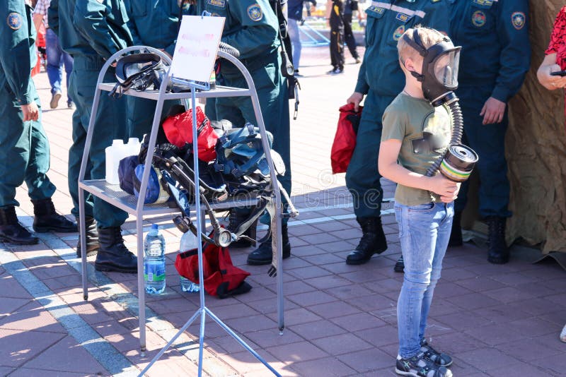 Een klein kind draagt een beschermend masker in een gasmasker en houdt een doos van gasmaskers in Wit-Rusland, Minsk, 08 08 2018 stock foto Een klein kind draagt een beschermend masker in een gasmasker en houdt een doos van gasmaskers in Wit-Rusland, Minsk, 08 08 2018 stock foto